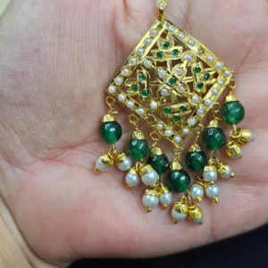 Close-up of handcrafted green maang tikka showing fine gold plated detailing